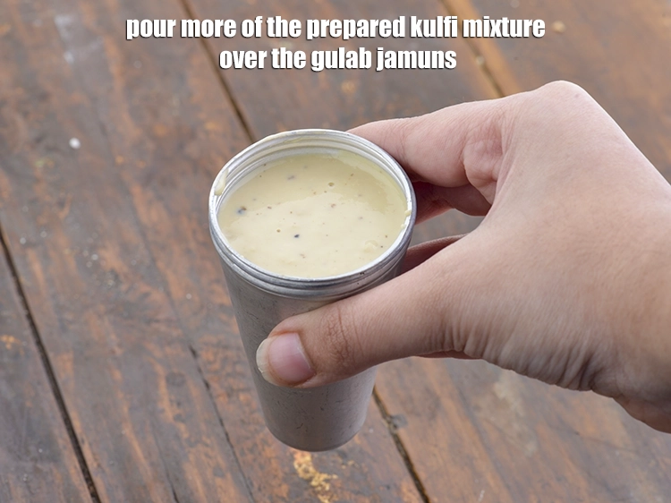 Step 14 – <p><span style="background-color:rgb(255,255,255);color:rgb(0,0,0);">Pour more of the prepared kulfi mixture over the </span><u>gulab jamuns.</u></p>