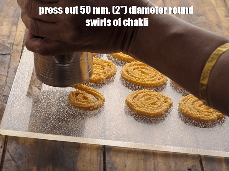 Step 13 – <p>Press out 50 mm. (2”) diameter round swirls of chakli onto a greased baking tray, …