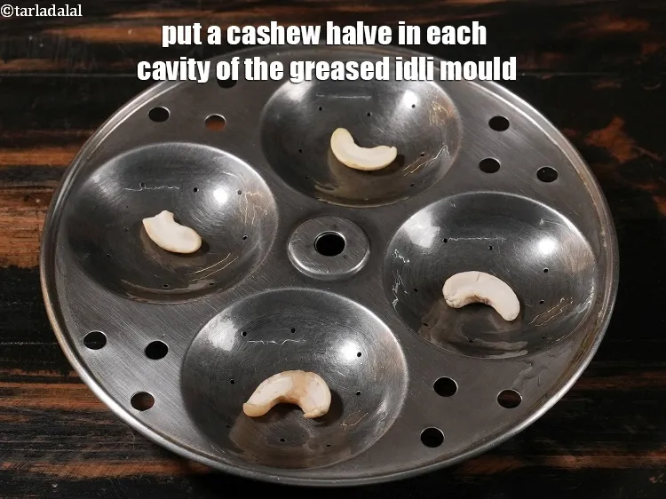 Step 49 – <p><span style="color:rgb(0,0,0);">Put a cashew halve in each cavity of the greased idli mould.</span></p>