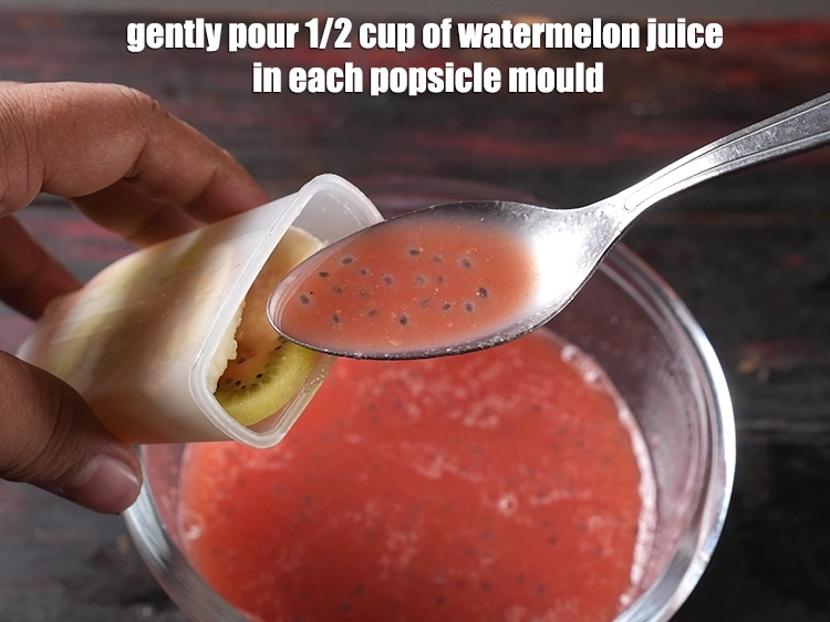 Step 10 – <p><span style="background-color:rgb(255,255,255);color:rgb(0,0,0);">Gently pour 1/2 cup of </span><a href="https://www.tarladalal.com/glossary-watermelon-juice-tarbuj-ka-ras-tarbuj-ka-juice-38i"><u>watermelon (tarbuj) juice</u></a><span style="background-color:rgb(255,255,255);color:rgb(0,0,0);"> in each popsicle mould.</span></p>