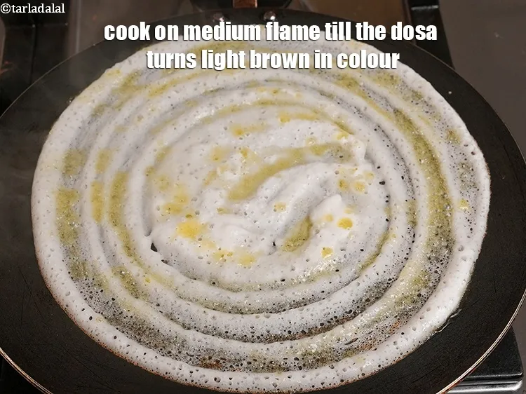 Step 9 – <p>Cook on medium flame till the dosa turns light brown in colour.</p>