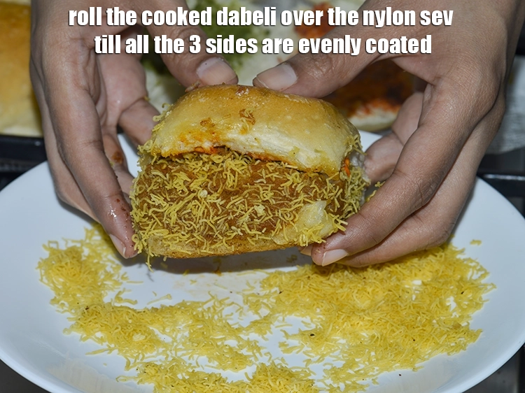 Step 9 – <p><span style="background-color:rgb(255,255,255);color:rgb(0,0,0);">Roll the cooked <strong>dabeli</strong> over the </span><a href="https://www.tarladalal.com/glossary-sev-1137i#ing_3489"><u>nylon sev</u></a><span style="background-color:rgb(255,255,255);color:rgb(0,0,0);"> till all the 3 …