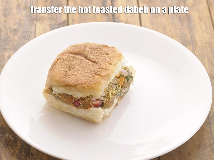 Step 29 – <p>Transfer the hot toasted dabeli on a plate.</p>
