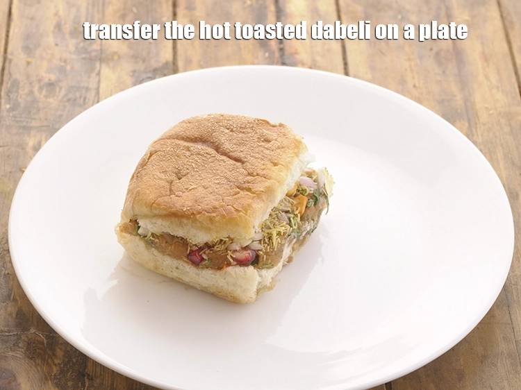 Step 45 – <p>Transfer the hot toasted <strong>dabeli</strong> on a plate.</p>