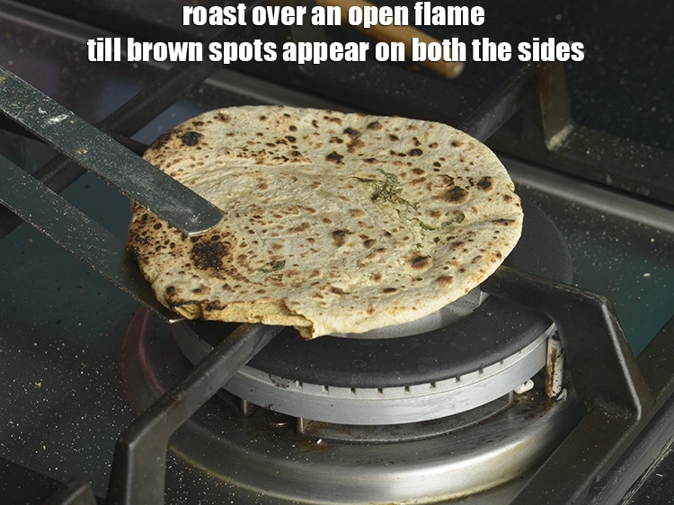 Step 52 – <p>Lift the paratha with a pair of flat tongs and roast over an open flame …