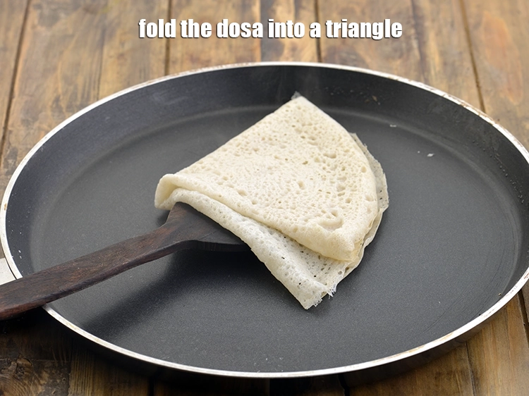 Step 12 – <p><span style="background-color:rgb(255,255,255);color:rgb(0,0,0);">Fold the <strong>dosa</strong> into a triangle.</span></p>