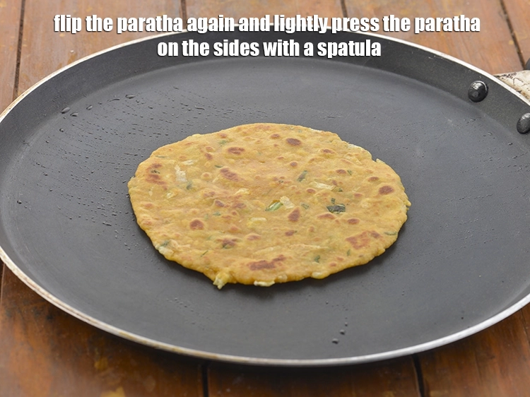 Step 24 – <p>Flip the <strong>paratha</strong> again and lightly press the paratha on the sides with a spatula, …