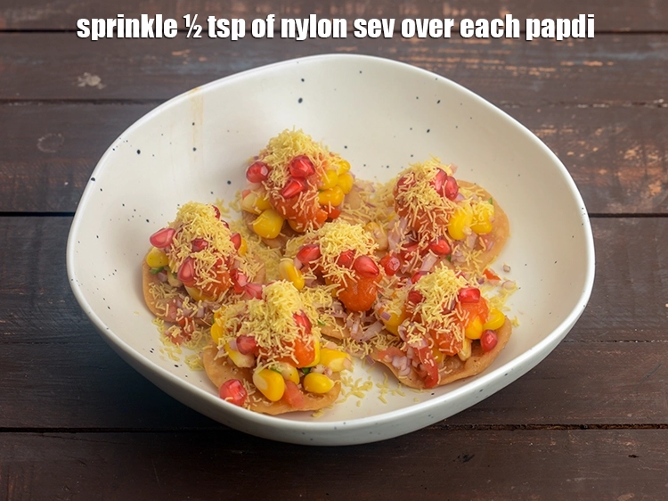 Step 29 – <p><span style="background-color:rgb(255,255,255);color:rgb(0,0,0);">Also sprinkle ½ tsp of <strong>nylon&nbsp;</strong></span><a href="https://www.tarladalal.com/sev-2791r"><strong><u>sev</u></strong></a><span style="background-color:rgb(255,255,255);color:rgb(0,0,0);">&nbsp;over each papdi.</span></p>