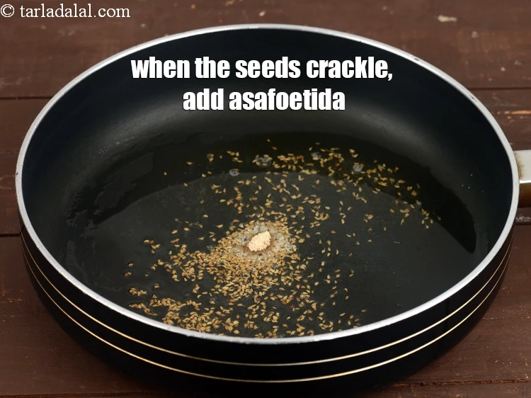 Step 7 – <p><span style="background-color:rgb(255,255,255);color:rgb(0,0,0);">When the seeds crackle, add a pinch of&nbsp;</span><a href="https://www.tarladalal.com/glossary-asafoetida-hing-113i"><u>asafoetida (hing)</u></a><span style="background-color:rgb(255,255,255);color:rgb(0,0,0);">.</span></p>