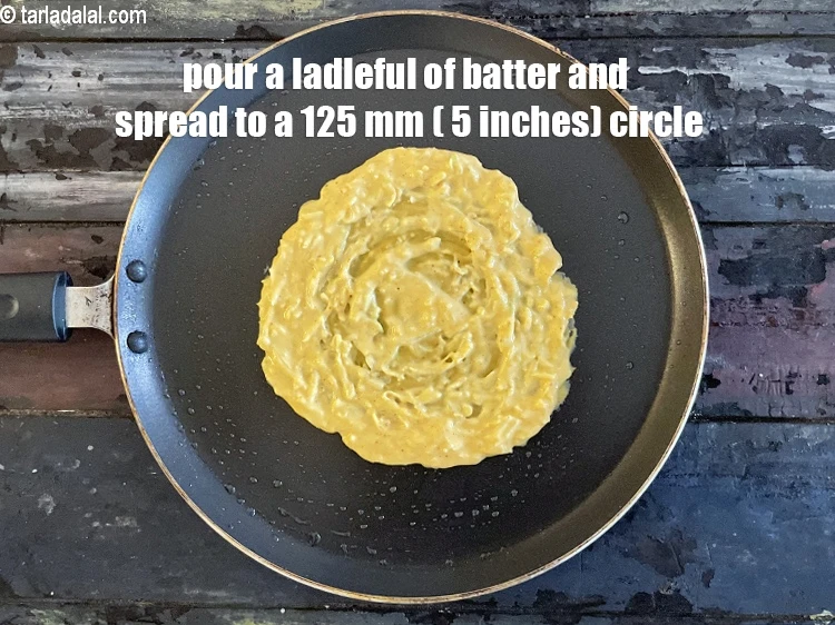 Step 14 – <p>Pour a ladle of the batter on the tava (griddle) and spread it evenly to …