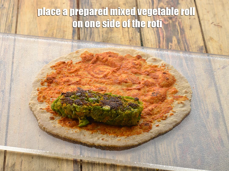 Step 25 – <p><span style="background-color:rgb(255,255,255);color:rgb(0,0,0);">Place a <strong>prepared mixed vegetable roll</strong> on one side of the roti.</span></p>