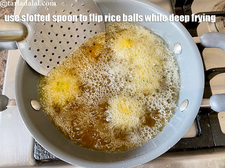 Step 17 – <html><head><meta charset="UTF-8"> </head><body><p>With the help of a slotted spoon, &nbsp;keep flipping the rice balls over …