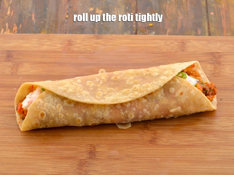 Step 51 – <p>Pick one end of the roti and start rolling it over the filling. Roll up …
