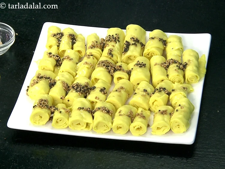 Step 30 – <p>Pour the tempering over the <strong>khandvis</strong> with the help of a spoon.</p>