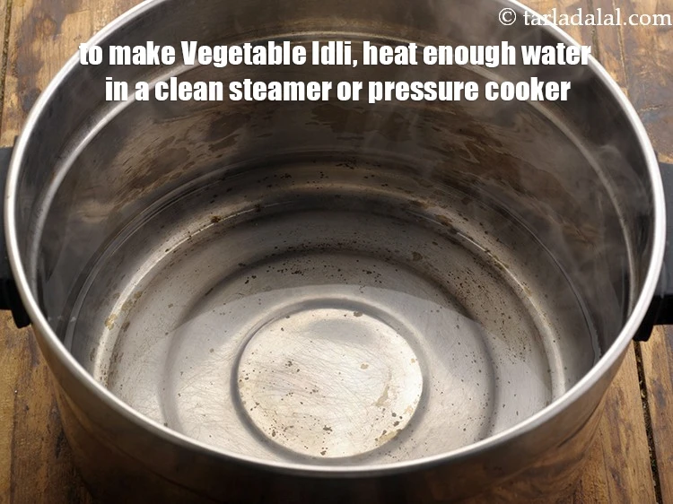 Step 23 – <html><head><meta charset="UTF-8"></head><body><p>To make&nbsp;<strong>Vegetable Idli,&nbsp;</strong>heat enough water in a clean steamer or pressure cooker.&nbsp;<br>&nbsp;</p></body></html>