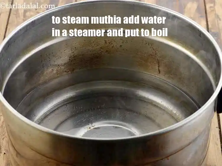 Step 21 – <p>To steam&nbsp;<strong>doodhi muthiya </strong>add water in a steamer and put to boil.</p>