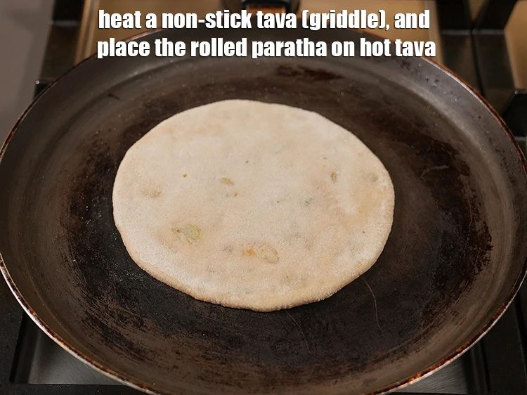 Step 17 – <p>Heat a non-stick tava (griddle), and place the rolled <strong>paratha</strong> on hot tava.</p>