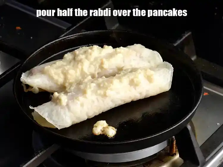 Step 27 – <p>Arrange 2 <strong>stuffed pancake</strong> rolls on top and pour half the <strong>rabdi</strong> over the <strong>pancakes</strong>.</p>