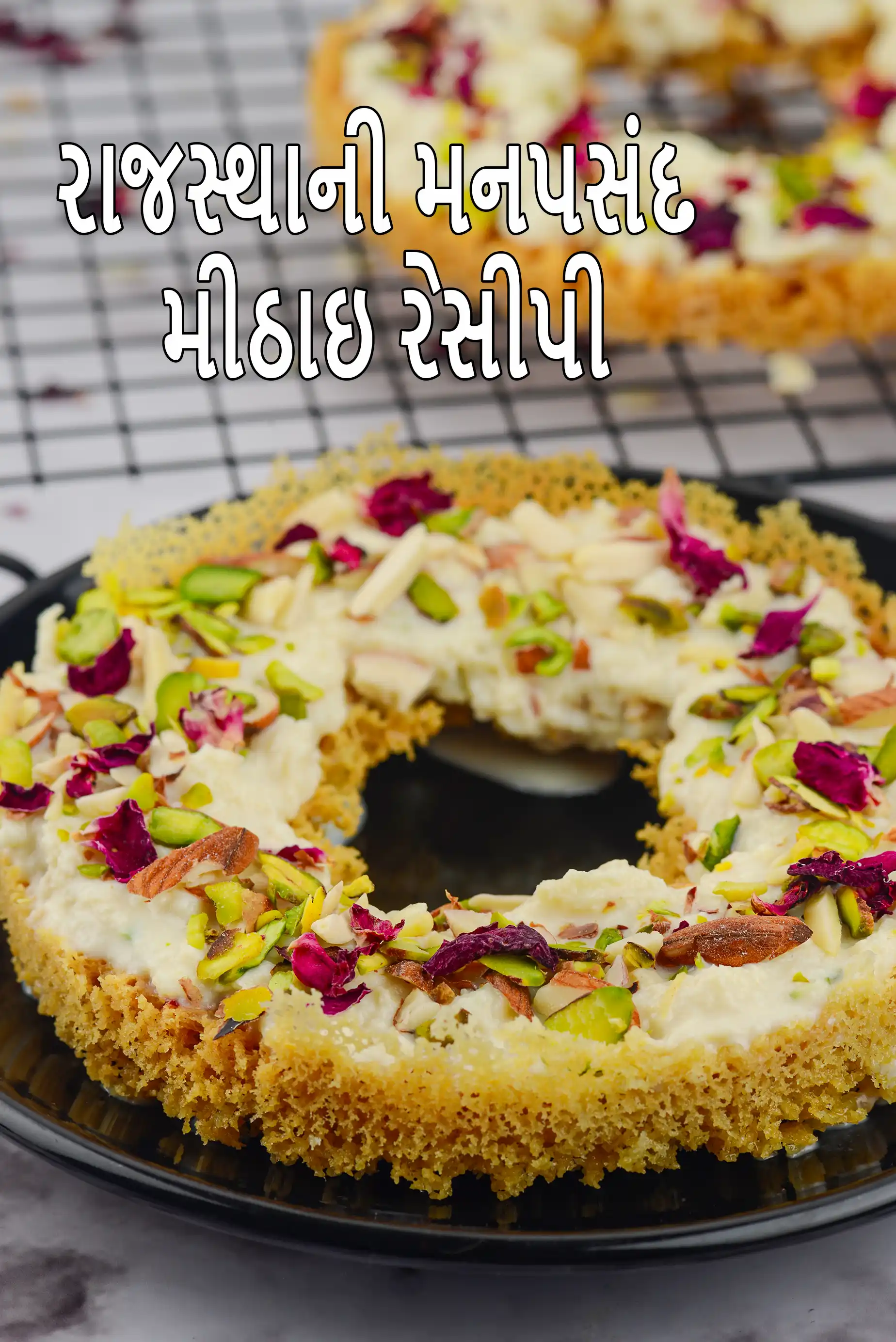 સોનેરી બેઝ પર ક્રીમી સફેદ પરતવાળી રાજસ્થાની મીઠાઈ, પિસ્તા, બદામ અને ગુલાબની પાંખડીઓથી સજાવેલી, કાળી થાળીમાં પીરસેલી, અને તસવીર પર “Rajasthani Mithai Recipes” લખાણ દર્શાવવામાં આવ્યું છે।