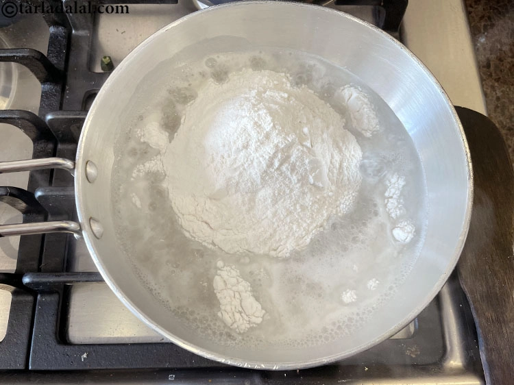 Step 5 – <p>પાણી ઉકળી જાય પછી, તેમાં ચોખાનો લોટ ઉમેરો. ચોખાના લોટની ભાખરીનો લોટ બનાવવા અને તેને …