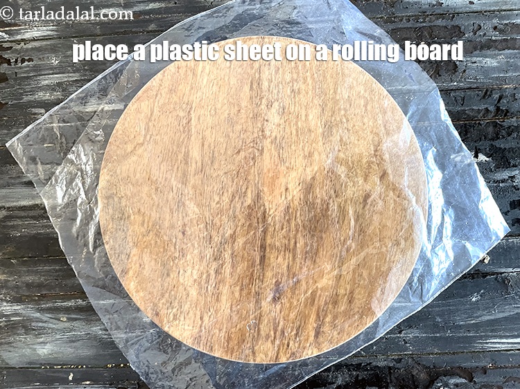 Step 11 – <p>જુવારની રોટલી રોલ કરવા માટેની પદ્ધતિ ૩, પગલું ૧. રોલિંગ બોર્ડ પર પ્લાસ્ટિક શીટ મૂકો.</p>