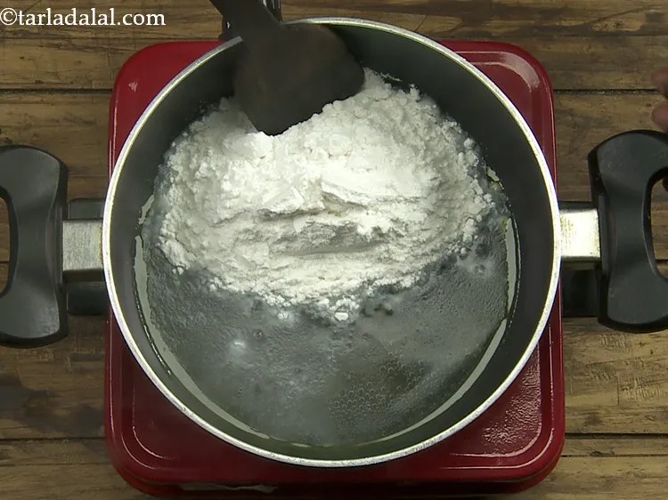 Step 3 – <p>ઉકળી જાય પછી તેમાં ચોખાનો લોટ ઉમેરો અને ચમચી વડે ઝડપથી મિક્સ કરો.</p>