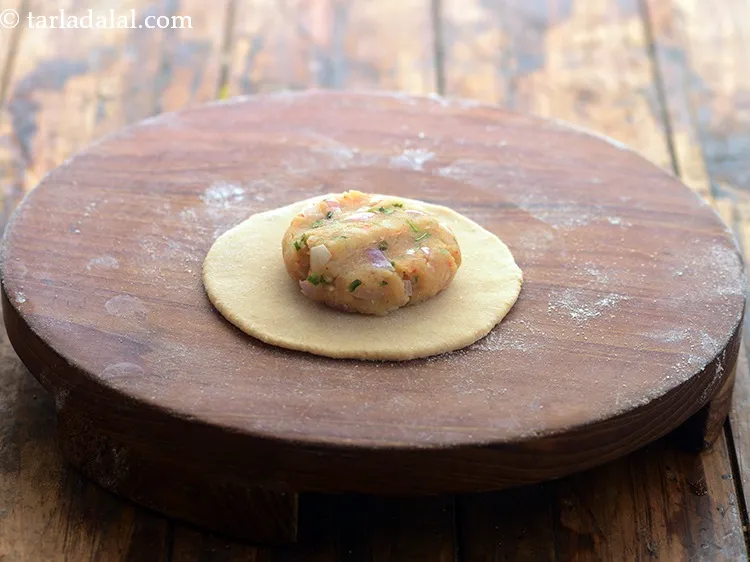 Step 20 – <p>સ્ટોફિંગના એક ભાગને બોલમાં ફેરવો. તેને રોલ કરેલા લોટની મધ્યમાં મૂકો અને હળવાશથી દબાવો.</p>