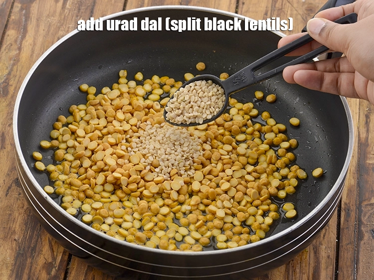 Step 3 – <p><span style="background-color:rgb(255,255,255);color:rgb(0,0,0);">1 ટેબલસ્પૂન </span><a href="https://www.tarladalal.com/glossary-urad-dal-split-black-lentil-gujarati-941i"><u>અડદની દાળ (urad dal)</u></a> ઉમેરો.</p>