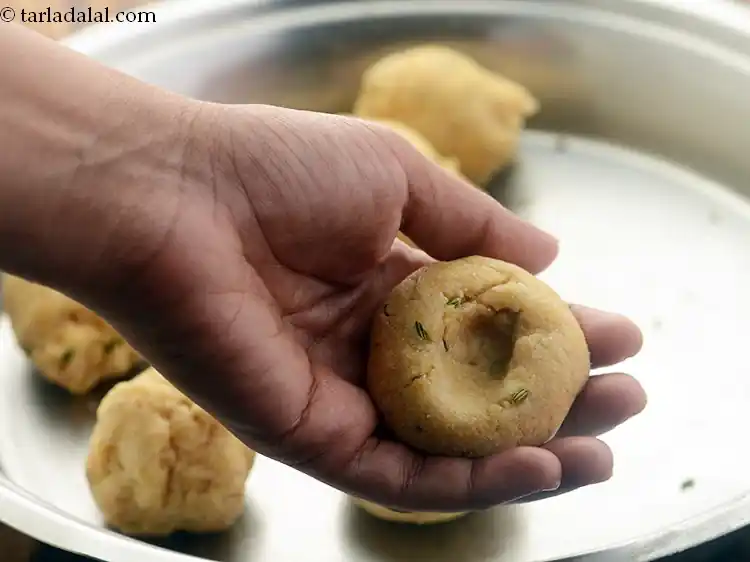 स्टेप 61 – <p>अपने अंगूठे का उपयोग करके बाटियों के केंद्र में एक …